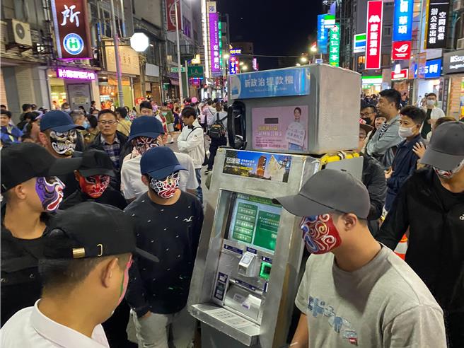 新竹市政府28日晚間舉辦萬聖節大遊行，但1名裝扮成「新政治提款機」的人裝道具全程遭8名八家將臉譜人包圍，綠營民代集體炸鍋，怒批已犯強制罪嫌。（陳育賢攝）