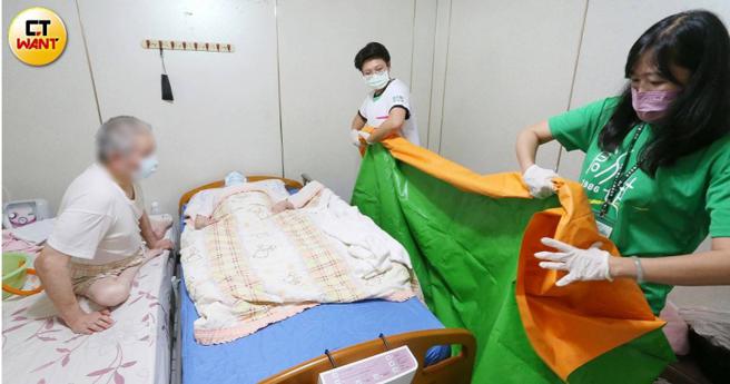 社区护理师黄秋桦与创世基金会文山分院院长邱子珆一起舖设防水垫，准备替汤奶奶进行「原床泡澡」。（图／赵世勋摄）