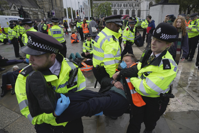 來自環保團體「攔住石油」的抗議人士在國會廣場周圍道路上緩慢步行約10分鐘，隨後遭倫敦都會區警察局逮捕。（圖/美聯社）
