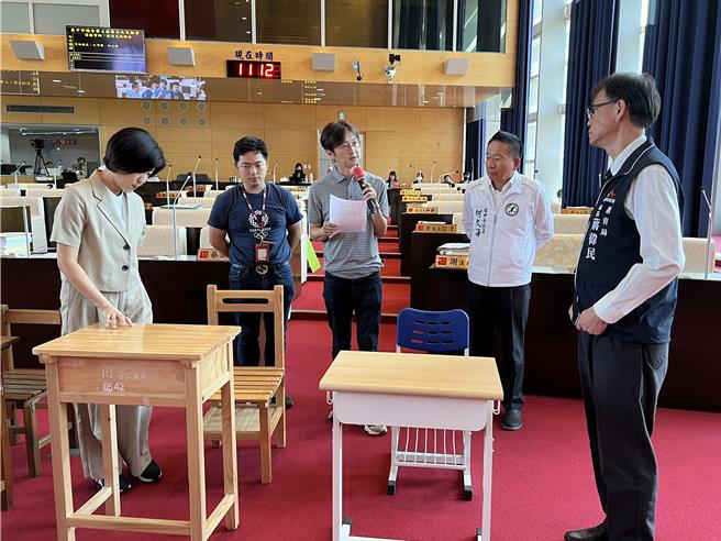 台中市议员江肇国(中)等人质询时将课桌椅搬到议事堂内，要求副市长王育敏(左)体验、坐坐看。(林欣仪摄)
