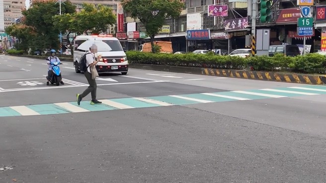 行人走在斑馬線上，看到救護車靠近，才嚇到停下腳步。（翻攝臉書我愛消防車）