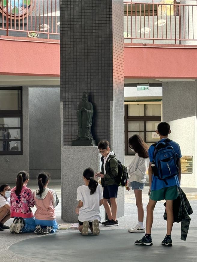 台北市延平國小校門口附近有學生跪在孔子銅像前，其實不是考不好被體罰，而是小朋友認為孔子象徵學業進步，段考期間習慣到銅像前拜拜。（延平國小提供／蔡佩珈台北傳真）