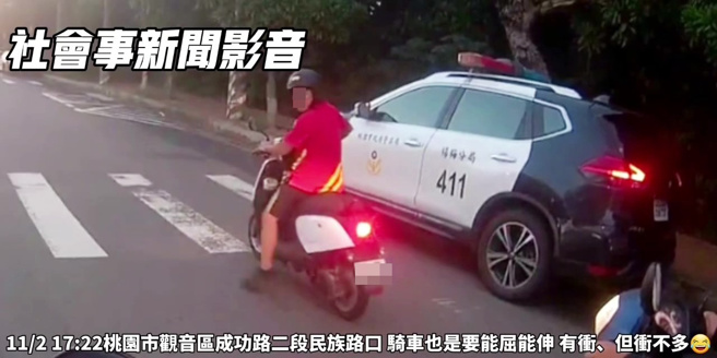 紅衣男子騎機車闖紅燈，只是旁邊就停了一輛警車，他衝到一半才發現有警察，突然停下，用腳慢慢倒退嚕回停等區。（翻攝社會事新聞影音）