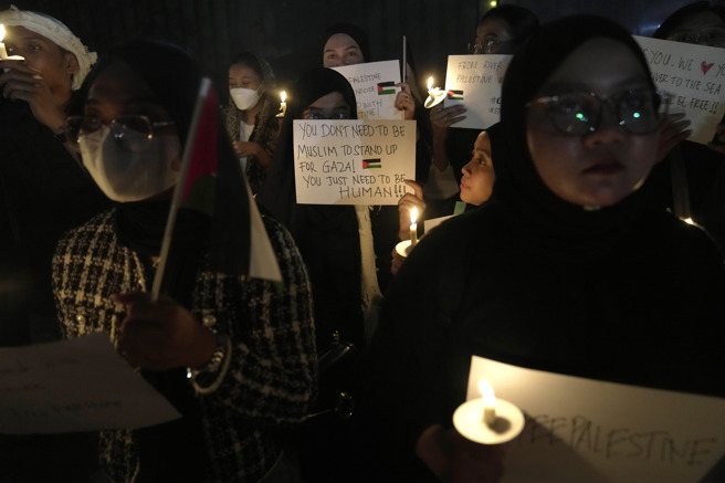 在印尼雅加达的巴勒斯坦大使馆前，民眾举着海报支持巴勒斯坦人。（图/美联社）
