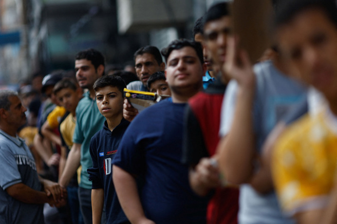 歷经以色列的连续轰炸，数以千计加萨人民为了生活所需，每天需排上好几个小时才能买到薄麵饼与其他生计用品。（图／路透社）