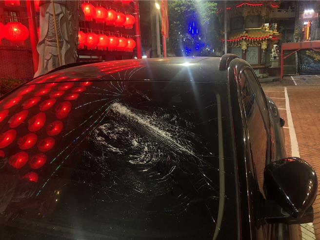 高雄前金区一处宫庙停车场内，一辆黑色小客车遭2名拿子持棍棒砸车，把挡风玻璃砸出长条状裂痕。（警方提供／任义宇高雄传真）