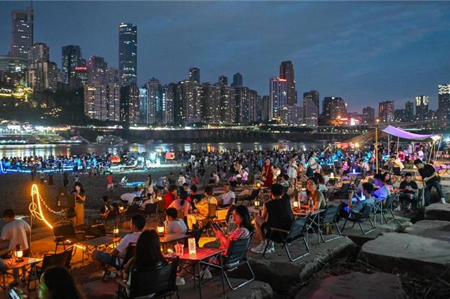 民眾在重庆江北嘴江滩公园夜市赏景、游玩。山城重庆的夏夜，「夜经济」升温，夜间消费活力涌动。（中新社）