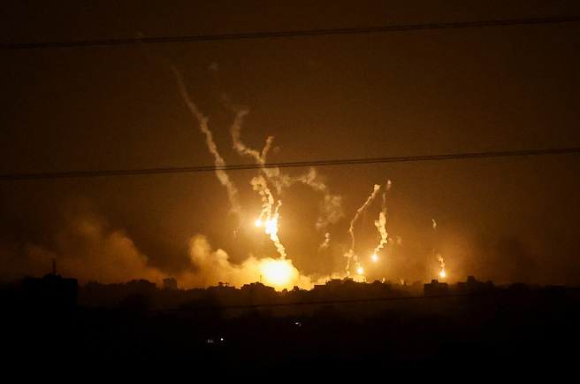以色列5日晚間對加薩走廊進行開戰以來最大轟炸，爆炸引發的濃煙及火焰照亮加薩走廊夜空。（圖／路透社）