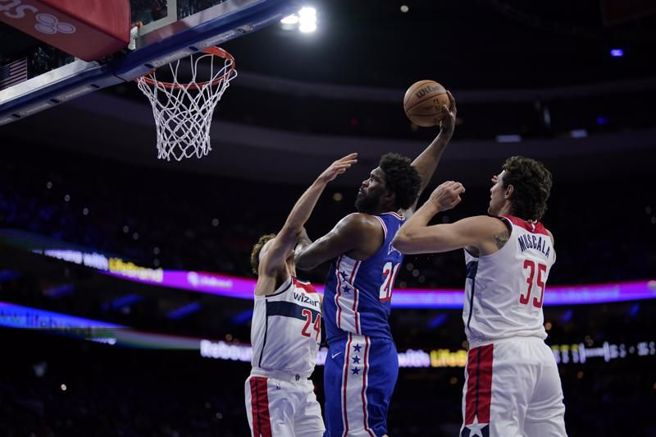 七六人中锋恩比德(中)飞身灌篮。（美联社）