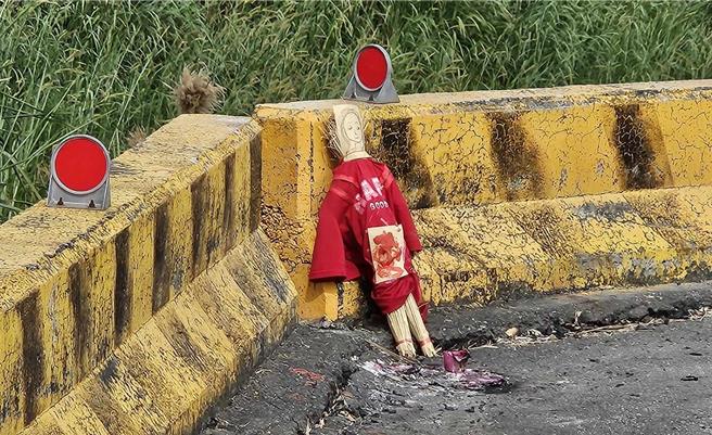 嘉義縣大林鎮三疊溪一處堤防路邊，有民眾發現一尊身穿紅衣的草人，頭部貼著紙畫的臉孔，地上有燒過的金紙，看起來十分詭異。（讀者提供∕呂妍庭嘉義傳真）