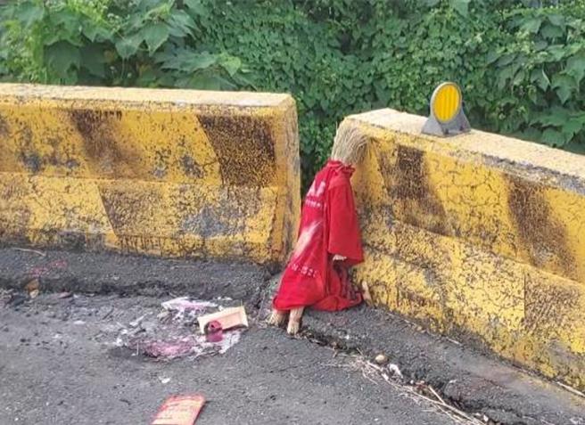 嘉義縣大林鎮三疊溪一處堤防路邊，有民眾發現一尊身穿紅衣的草人，頭部貼著紙畫的臉孔，地上有燒過的金紙，看起來十分詭異。（讀者提供∕呂妍庭嘉義傳真）