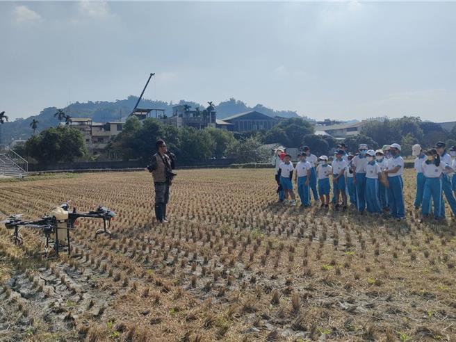 台中市大里区瑞城国小六年级学生9日上午前往雾峰参访，青农黄绪为操作智慧科技农业之植保机示范稻田喷药，1分地约10分钟就完成喷药，令在场学童惊奇连连。（潘虹恩摄）