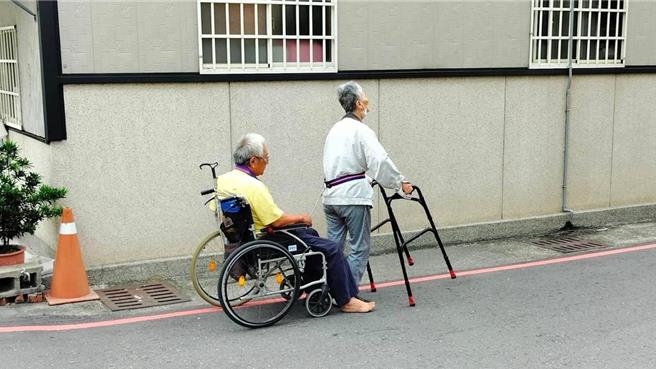 彰化市长林世贤12日在彰化市仁爱路目击１名以助行器行走的阿嬷腰间缠绳，拉着坐在轮椅上的阿公缓缓前进的温馨画面。（翻摄彰化市长林世贤脸书／孙英哲彰化传真）