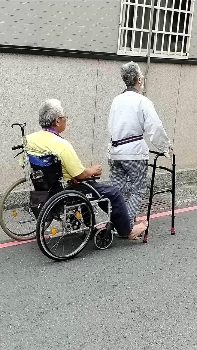 彰化市长林世贤12日在彰化市仁爱路目击１名以助行器行走的阿嬷腰间缠绳，拉着坐在轮椅上的阿公缓缓前进的温馨画面。（翻摄彰化市长林世贤脸书／孙英哲彰化传真）