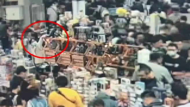 男子伸手将高处的哥吉拉公仔取下，趁店员没注意就离开了会场。（警方提供）