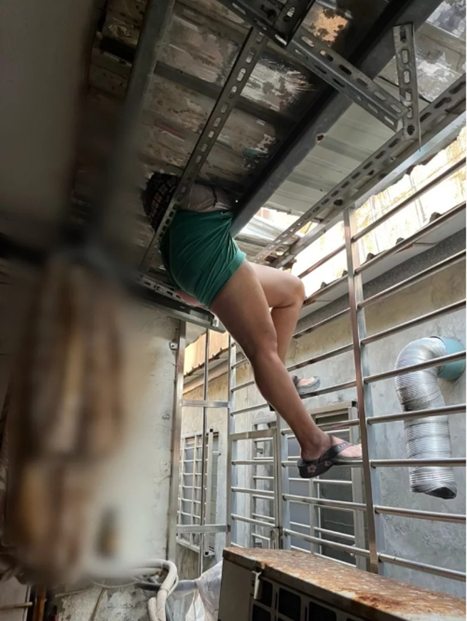 偷钱的女儿卡在遮雨棚，屋内只看到一双腿。（翻摄画面）