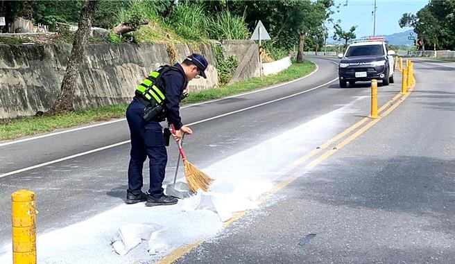 台东鹿野分驻员警在车流中扫除路面白沙，动作迅速俐落，来往车辆也不时喊话加油、比「讚」手势打气。（台东县警察局提供／萧嘉蕙台东传真）