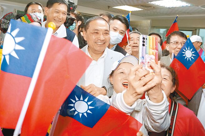 国民党总统参选人侯友宜（中）13日出席「新住民团体侯援会」成立大会，进场时被支持群眾包围自拍合影。（黄世麒摄）