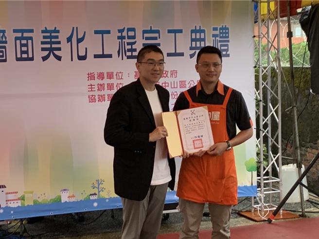 基隆市外木山一带的文明路挡土墙因为年久脏乱，由基市府结合特力屋与文化大学执行美化工程，16日举行完工典礼。图为基隆市长谢国梁（左）颁发感谢状予业者特力屋课长沈锜丰。（徐佑升摄）