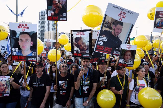 10月7日遭哈玛斯掳走的大批人质迄今仍下落不明，他们的家属手拿失踪亲人照片游行数日之后今天抵达耶路撒冷，要求以色列政府给个交代。(图/ 路透社)