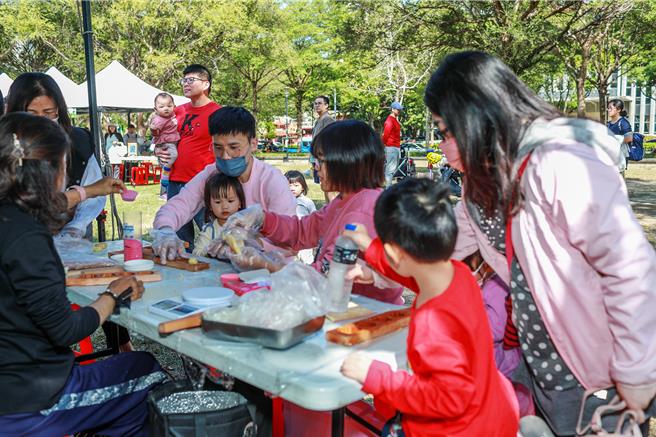 新竹县政府农业处19日在竹北水圳森林公园活动草坪举办「第三届农村藏食节」，亲子在美食摊位体验手作「红粄」等客家美食。（罗浚滨摄）