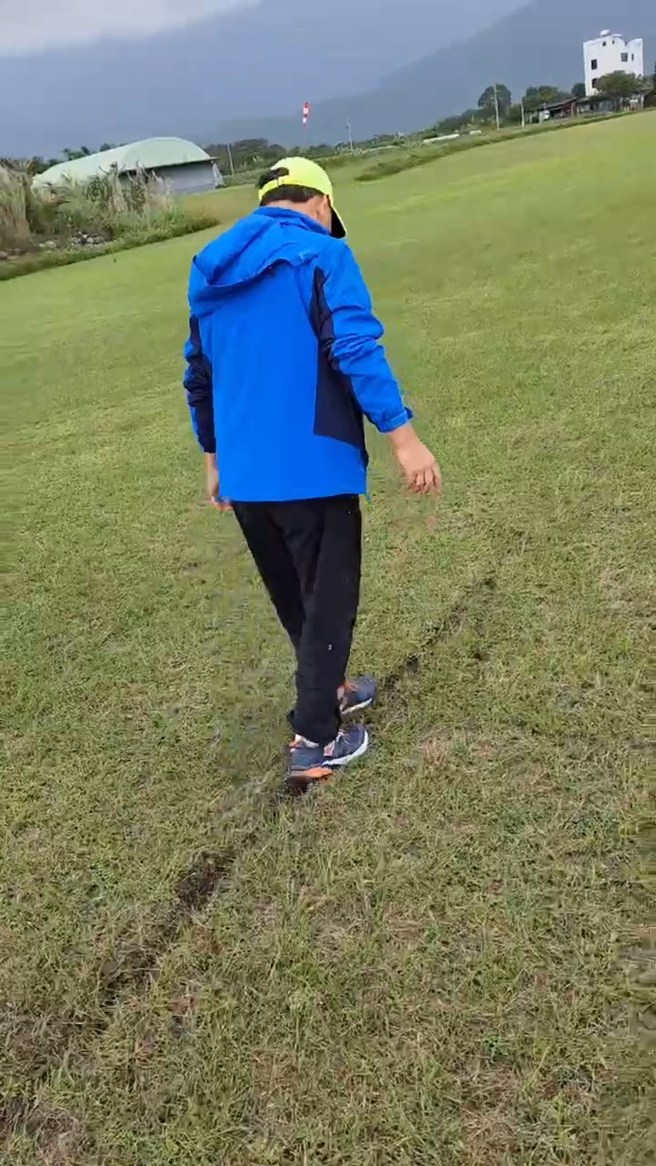 一名男子在跑道上用脚踩土，要将轮胎的沟痕填平。（翻摄爆料公社）