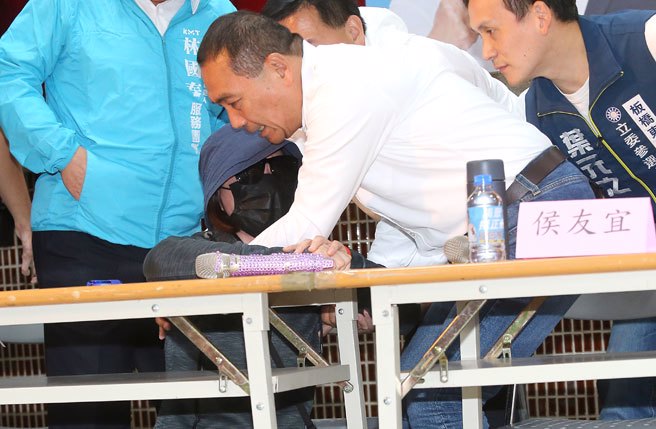 国民党总统参选人侯友宜（右）21日前往新北市板桥国光公园活动中心出席打诈政策发布会，遭骗一千五百万的民眾下跪向侯友宜陈情希望能救救她。（陈君玮摄）