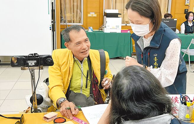 台南市立委选举登记第一天，无政党推荐的永续策略管理师侯陆太（左），单枪匹马坐着轮椅拔得头筹完成第一选区立委参选登记。（洪荣志摄）