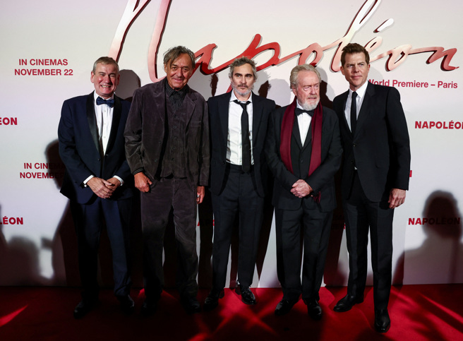 由金獎大導雷利史考特（Ridley Scott）執導的好萊塢史詩鉅作「拿破崙」（Napoléon）電影即將上映，卻在法國引發爭議。圖為電影導演與製片於法國巴黎全球首映合影。（圖／路透社）