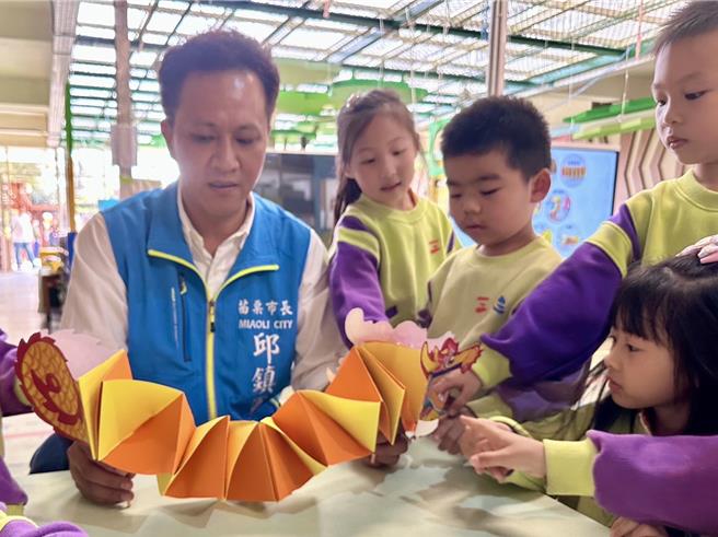 苗栗市长邱镇军教导幼童制作纸糊龙。（苗栗市公所提供／李京升苗栗传真）