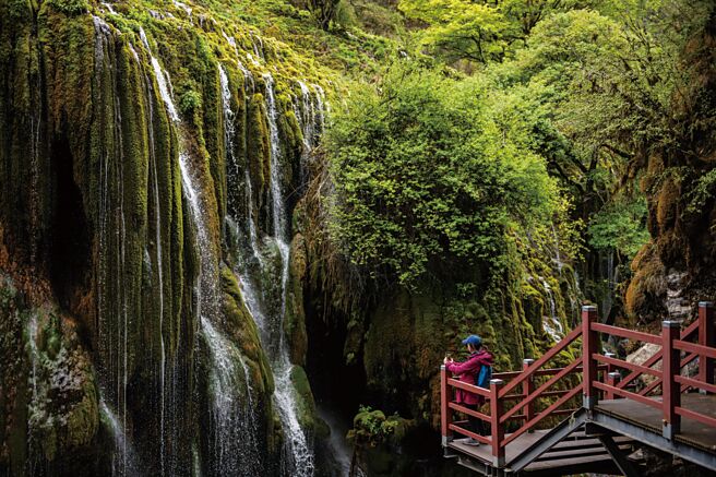 滇藏铁路丽香段即将通车，预料也将为香格里拉带来更多旅游人潮。图为游客在当地七彩瀑布前拍照。（新华社）