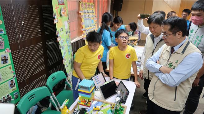 海东国小学生向市长黄伟哲说明机器人作品。(曹婷婷摄)