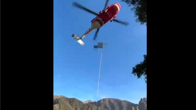 受伤的日本登山客被背负到吊挂点，由直升机吊挂送下山。（嘉义县消防局提供／廖素慧嘉县传真）