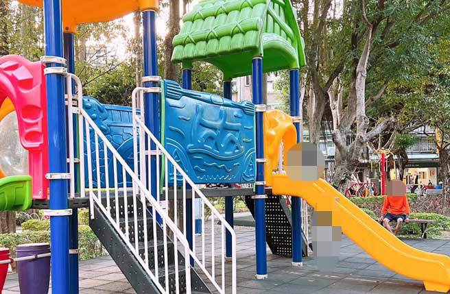 身穿橘衣赤脚的阿伯坐在很多小朋友在玩的溜滑梯旁边抽菸，接着随手抱起1名1岁男童。（翻摄脸书我是中和人）