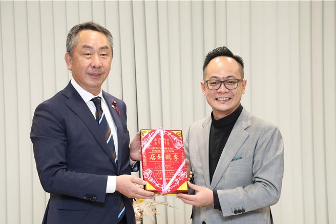 日本全国市议会议长会会长、神户市议会议长坊恭寿（左）24日率团共12人参访基隆市议会，由议长童子玮（右）与副议长杨秀玉接待。图为童子玮致赠基隆名产凤梨酥给坊恭寿。（童子玮办公室提供／徐佑升基隆传真）