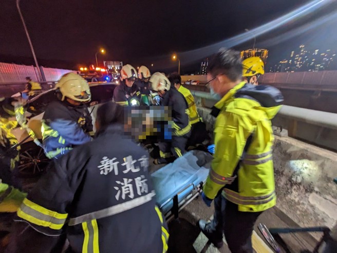 车祸现场白色轿车自撞分隔护栏，驾驶救出无生命迹象。（消防局提供）