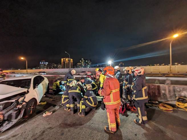 车祸现场白色轿车自撞分隔护栏，驾驶救出无生命迹象。（消防局提供）