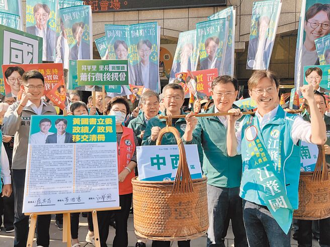 民进党提名台中六选区立委参选人江肇国，23日由现任立委黄国书、立法院副院长蔡其昌陪同登记，黄国书并将装有中西东南区政策清单的扁担交给江，象徵传承、交棒。（林欣仪摄）