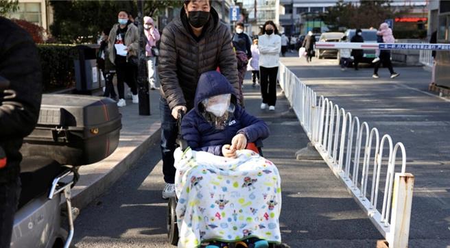 2023年11月24日，中国北京，一名男子在儿童医院外用轮椅推着一名盖着毯子的儿童。在新冠疫情首批讯号在中国出现将近4年后，在中国北方，尤其是在儿童中，呼吸道传染病大增。（路透）