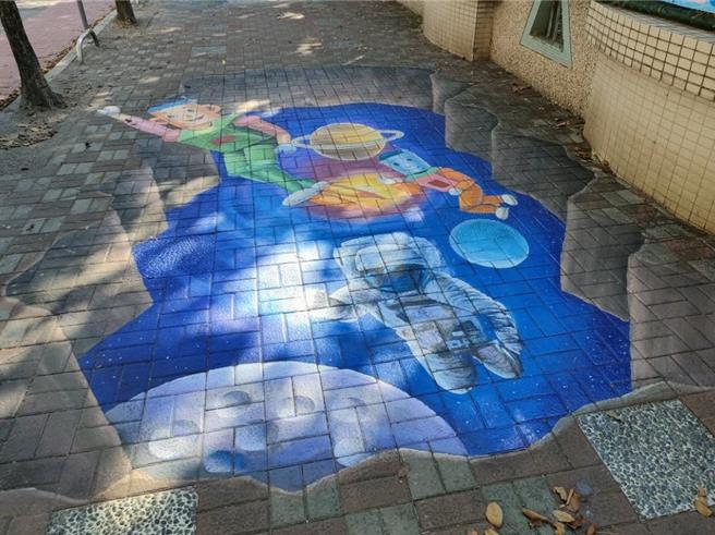 台中市大里区立新国小外围人行道近日出现1幅「星球探索」3D立体彩绘，洞底是美丽的夜空与星球，机器人和太空人徜徉其中，生动吸睛，令居民大讚「好美」。（潘虹恩摄）