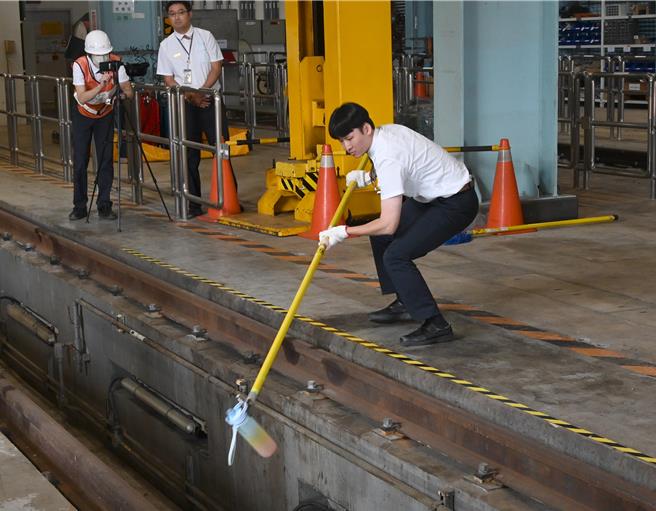 台灣高鐵29日在燕巢總機廠舉行安全演練和競賽，圖為拾物棒競技，站務員以拾物棒撿起水壺。（林瑞益攝）