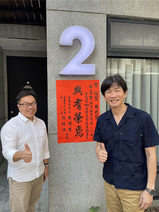 文化局副局长陈修程(左)29日前往「Studio2 Animation Lab」工作室张贴红榜，向邱立伟(右)道贺。(台南市文化局提供／曹婷婷台南传真)