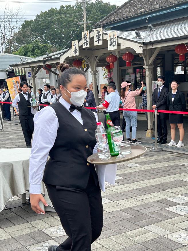 餐厅服务生单手端托盘得绕着餐桌S型竞走，仪态也是评分项目。（杨静茹摄）