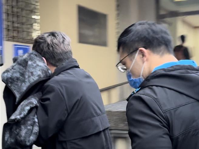 新北市警察局三重警分局侦查队林姓侦查佐（左）被移送新北地检署复讯，全程以外套遮头快闪。（柯毓庭摄）