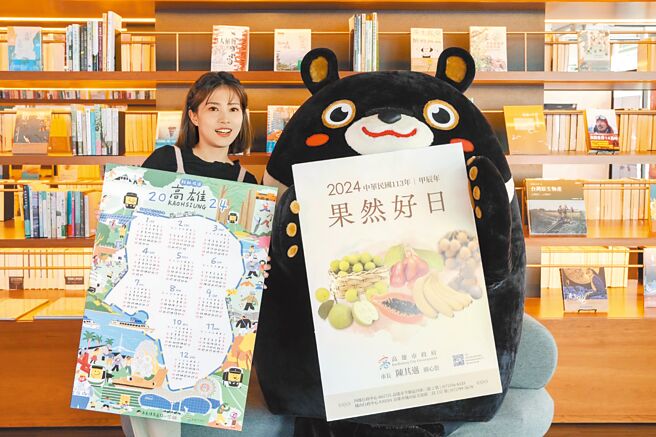 高市府发言人周璟瑜（左）特别与吉祥物高雄熊（右）携手抢先开箱「轻轨成圆」手绘年历与「果然好日」水果月历。（高市府新闻局提供／洪浩轩高雄传真）