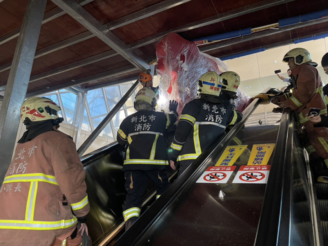 今（4）日下午14时许，新北市板桥捷运站3号出口发生一起意外，一名30岁男子抱一个大型装置物品搭乘手扶梯，大型装置物品不慎卡在天花板，导致男子被大型装置物品夹困在手扶梯上。（翻摄画面）