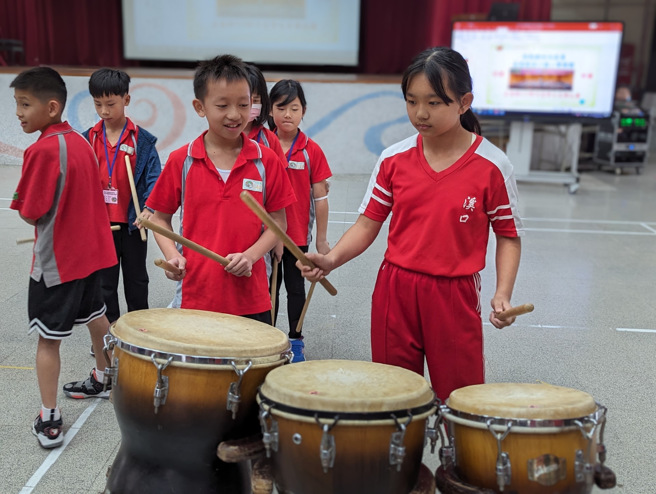 嘉义溪口国小陈媺慈校长热情邀请臺北溪口的学生上台体验击大鼓的乐趣。(照片/臺北溪口国小提供)