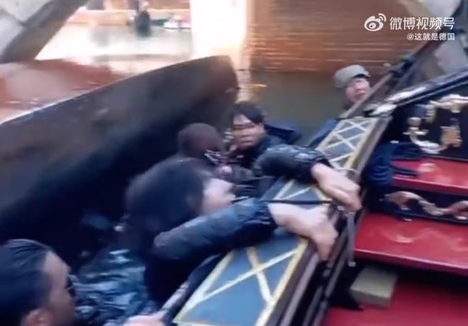 一名女游客怕水，神情慌张地抓着船身，试图爬上船，还害怕地大叫， 不过手还是紧紧握着手机不放。（翻摄微博）