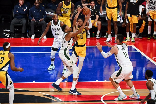 遭遇阿提托康波防守的哈利伯顿把球外传给队友。(路透)