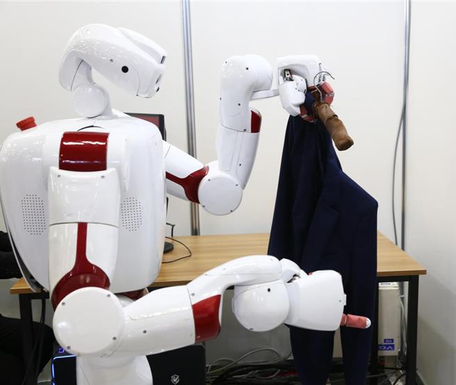 在今年日本東京舉辦的日本國際機器人展上，早稻田大學的機器人展示往衣架上掛衣服。（摘自新華社）